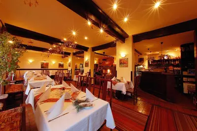 a restaurant with white tables and a bar in the background at Park Hotel Pruhonice in Pruhonice