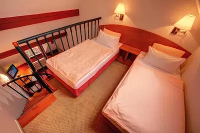 a small room with two beds and a staircase at Park Hotel Pruhonice in Pruhonice