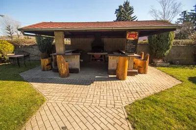 a pavilion with a table and a grill in a yard at Hotel Sport in Štětí