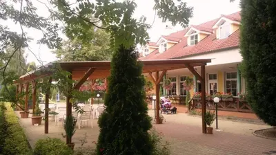 a pavilion in front of a house with a person sitting on a bench at Penzion Oáza in Štětí
