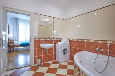 a bathroom with a tub and a sink and a washing machine at Charles Bridge Suites in Prague