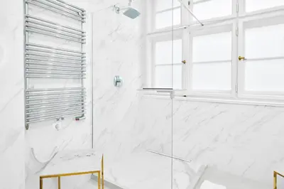 a white bathroom with a shower and a chair at Palace Dlouhá Apartments - Old Town in Prague