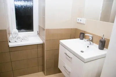 a white bathroom with a sink and a window at Sunny Aircon Apartment in the Centre of Slaný in Slaný