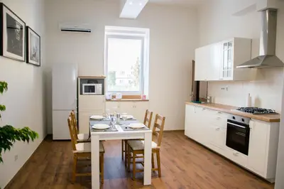 a kitchen with a table and chairs and a kitchen with white cabinets at Sunny Aircon Apartment in the Centre of Slaný in Slaný