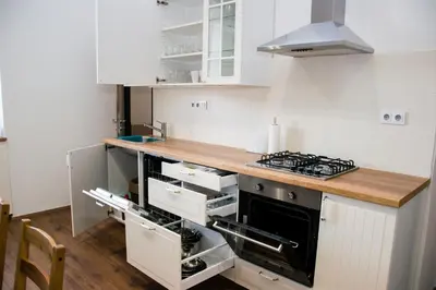 a kitchen with white cabinets and a wooden counter top at Sunny Aircon Apartment in the Centre of Slaný in Slaný