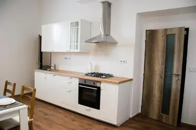 a kitchen with white cabinets and a stove top oven at Sunny Aircon Apartment in the Centre of Slaný in Slaný