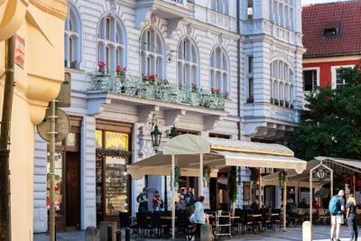 a street in a city with people sitting at tables at Aurus by Adrez in Prague