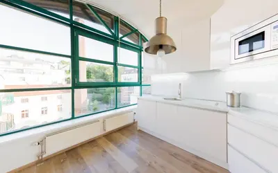 a kitchen with white cabinets and a large window at Romantic studio with jacuzzi in Prague
