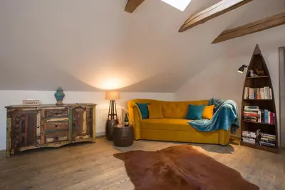 a living room with a yellow couch and a book shelf at Gigantic Boho Chic 3 Bedroom 3 Bathroom Loft with Hanging Chair in Prague
