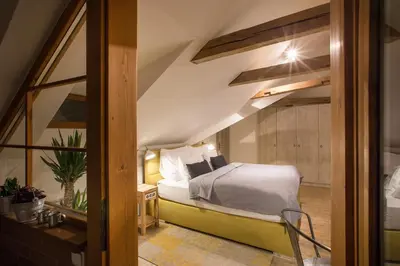 an attic bedroom with a bed and a window at Gigantic Boho Chic 3 Bedroom 3 Bathroom Loft with Hanging Chair in Prague