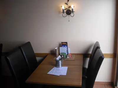 a dining room table with two chairs and a table with a lamp at Penzion Nová Hospoda in Prague
