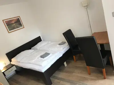 a small bed in a room with two chairs and a table at Penzion Nová Hospoda in Prague
