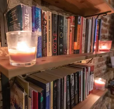 a book shelf with a candle and books at The RoadHouse Prague in Prague