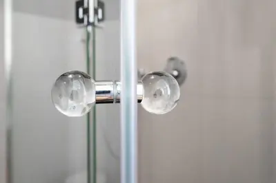 a glass shower door with two knobs on it at Arch II at Wenceslas in Prague