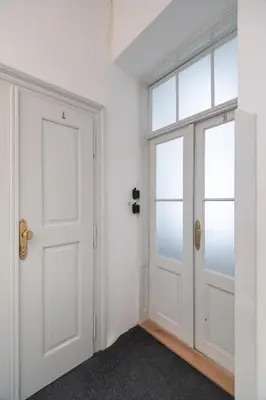 an empty room with a white door and windows at Quiet apartment in the heart of Old Town centre in Prague