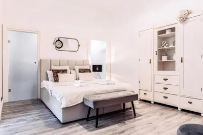 a white bedroom with a large bed and a bench at Wenceslas Square / Main Station - NEW STUDIO***** in Prague