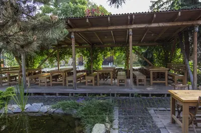 a wooden pavilion with tables and chairs in a garden at Penzion Ve stoleti in Loděnice