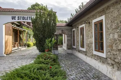 a stone house with a cobblestone street next to a building at Penzion Ve stoleti in Loděnice