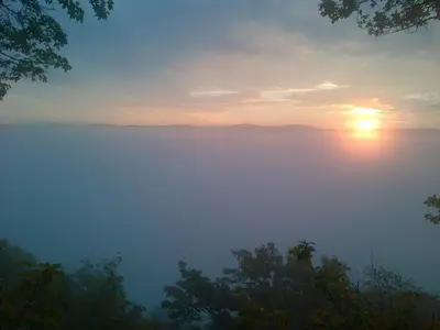 a misty sunrise with the sun rising over the mountains at Penzion a Restaurace Nad Hradem in Křivoklát