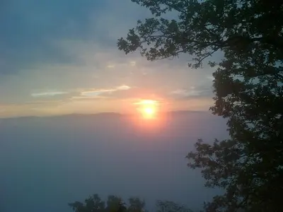 a misty sunrise with the sun in the sky at Penzion a Restaurace Nad Hradem in Křivoklát