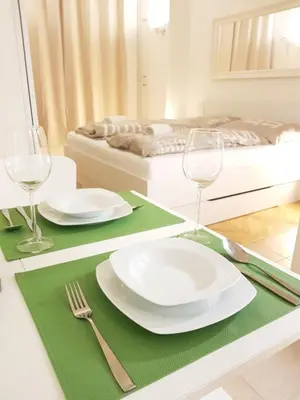a dining table with plates and glasses and a bed at Cozy studio with parking near city center in Prague