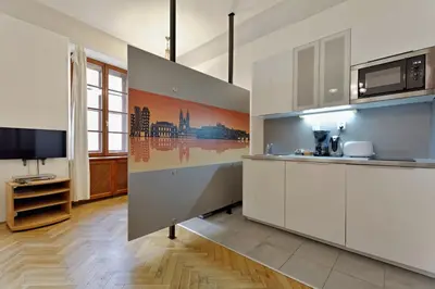 a kitchen with white cabinets and a tv in a room at Historic Centre Apartments VIII in Prague