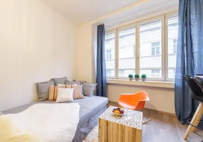 a bedroom with a bed and a chair and a window at Central Prague Crown Apartments in Prague