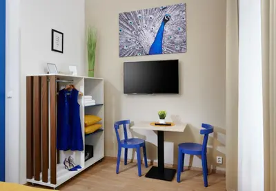 a room with a table and blue chairs and a tv at City Nest Apartments by Adrez in Prague