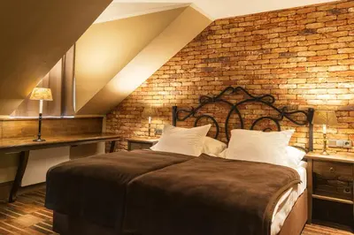 a bedroom with a large bed with a brick wall at Park Hotel Popovicky in Popovičky