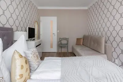 a bedroom with a white bed and a couch at Pastel Art Deco 3BDR Ruterra Apt in Prague