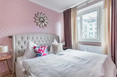 a bedroom with a white bed and a pink wall at Pastel Art Deco 3BDR Ruterra Apt in Prague