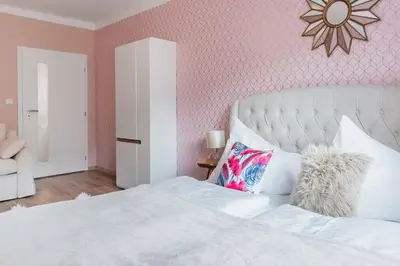 a bedroom with a white bed with a pink wall at Pastel Art Deco 3BDR Ruterra Apt in Prague