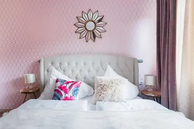 a bedroom with a white bed with a pink wall at Pastel Art Deco 3BDR Ruterra Apt in Prague