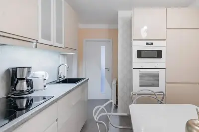 a kitchen with white cabinets and a sink at Pastel Art Deco 3BDR Ruterra Apt in Prague