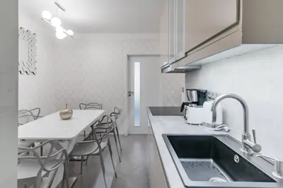 a kitchen with a sink and a table with chairs at Pastel Art Deco 3BDR Ruterra Apt in Prague
