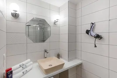 a white tiled bathroom with a sink and a mirror at Pastel Art Deco 3BDR Ruterra Apt in Prague