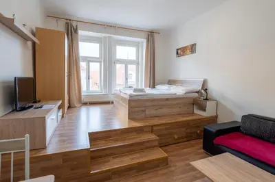 a bedroom with a bed and a couch and a tv at Downtown Apartments in Prague