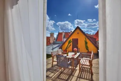 a balcony with chairs and a table and a yellow house at Ericsson Palace in Prague