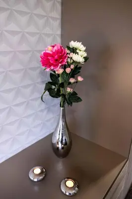 a vase of flowers on a table with two candles at Exclusive Pension Vista Mlada Boleslav in Bradlec