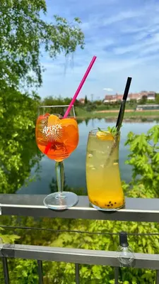 two cocktails sitting on a railing with a view of a river at Exclusive Pension Vista Mlada Boleslav in Bradlec