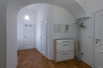 a kitchen with white walls and wooden floors at Apartman Carolinum in Prague