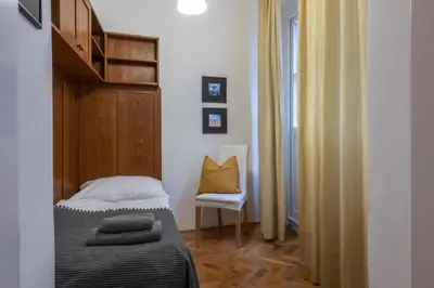 a small bedroom with a bed and a chair at Apartman Carolinum in Prague