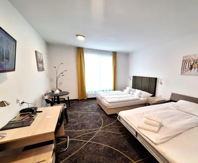 a bedroom with a bed and a desk and a tv at Hotel Valcha in Prague