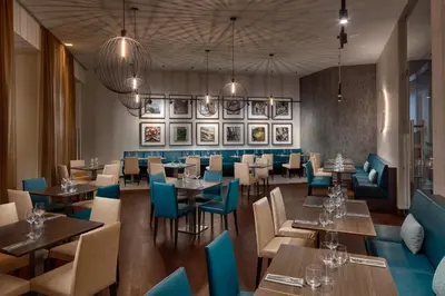a restaurant with wooden tables and blue chairs at Hermitage Hotel Prague in Prague