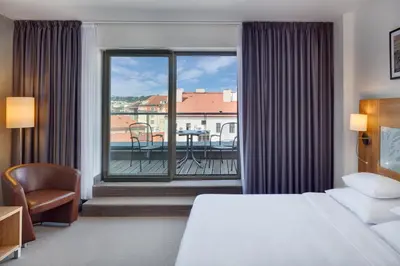 a hotel room with a bed and a view of a balcony at Hermitage Hotel Prague in Prague