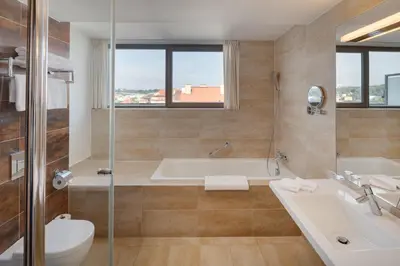 a bathroom with a tub and a toilet and a sink at Hermitage Hotel Prague in Prague