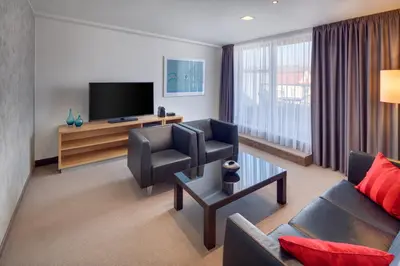 a living room with a couch and a tv at Hermitage Hotel Prague in Prague