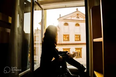 a woman looking out a window at a building at Best Spot Hostel in Prague