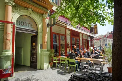 a group of people sitting at tables outside a building at Best Spot Hostel in Prague