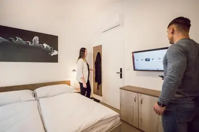 a man and woman standing in a bedroom with a tv at Kings Residence in Prague